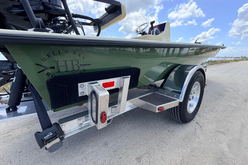 Slide: The Image of 2025 Hell's Bay Professional boat on trailer, green hull, clear sky background. - 25