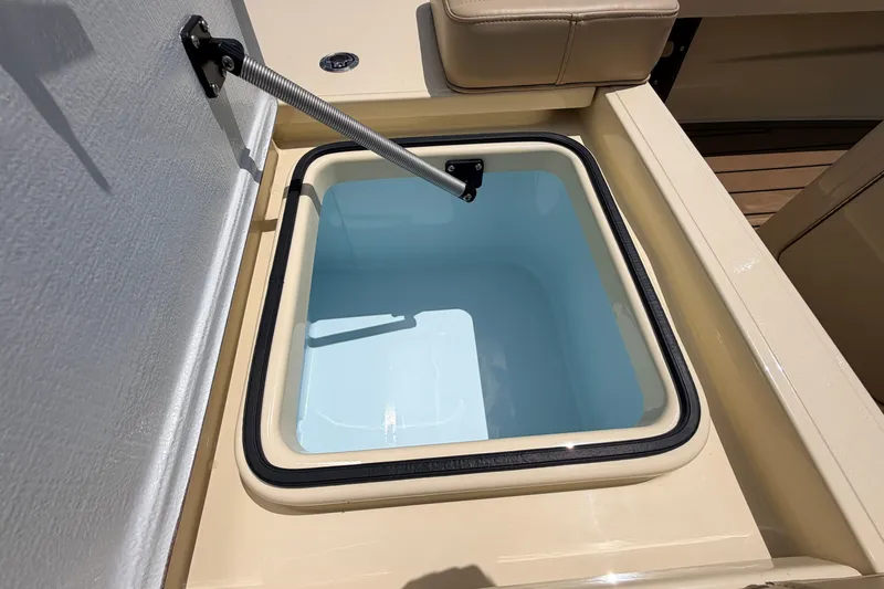 Slide: The Image of Livewell compartment on a 2025 Hell's Bay Professional boat, featuring a secure lid and cushioned seat. - 61