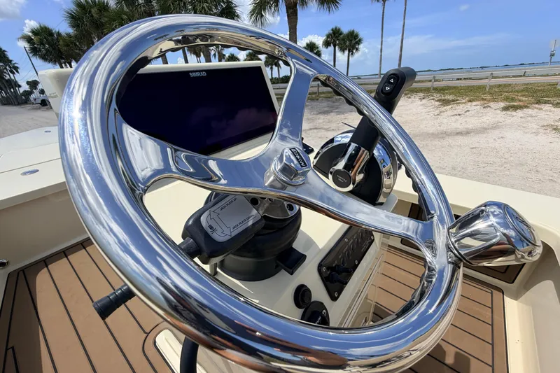 Slide: The Image of 2025 Hell's Bay Professional boat steering wheel with Simrad display, docked near palm trees. - 49