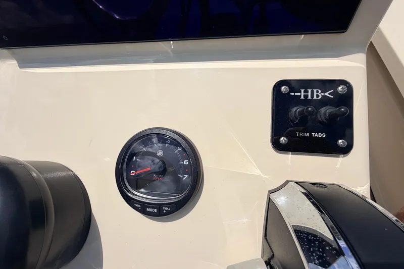 Slide: The Image of Dashboard of 2025 Hell's Bay Professional boat with RPM gauge and trim tab controls. - 47