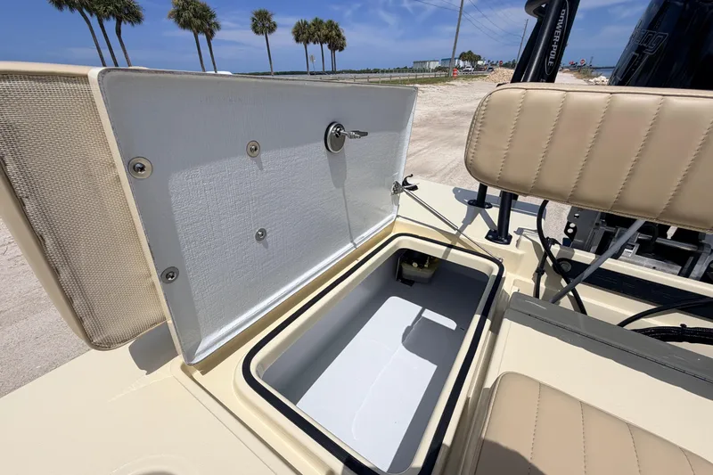 Slide: The Image of Open storage compartment on 2025 Hell's Bay Professional boat, with beige seating and palm trees in background. - 58