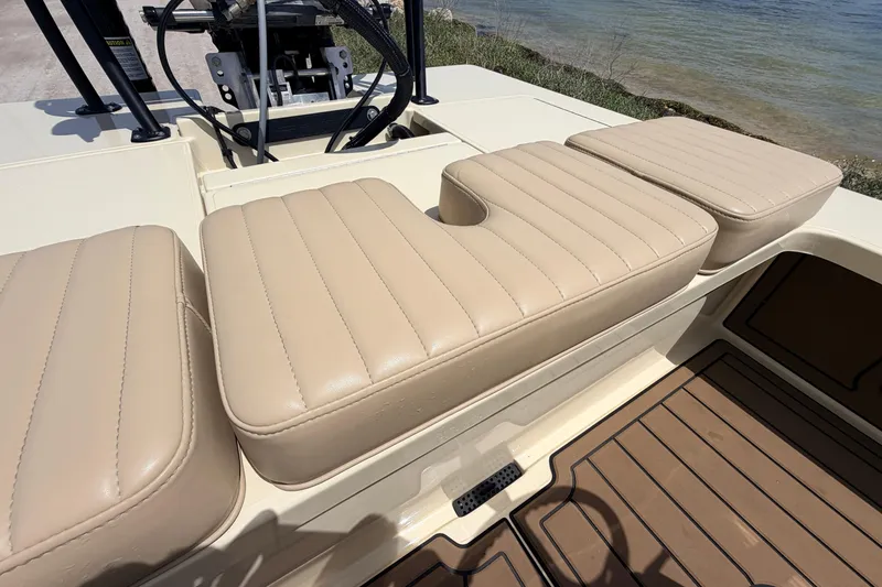 Slide: The Image of 2025 Hell's Bay Professional boat with beige cushioned seating and wooden deck near water. - 59
