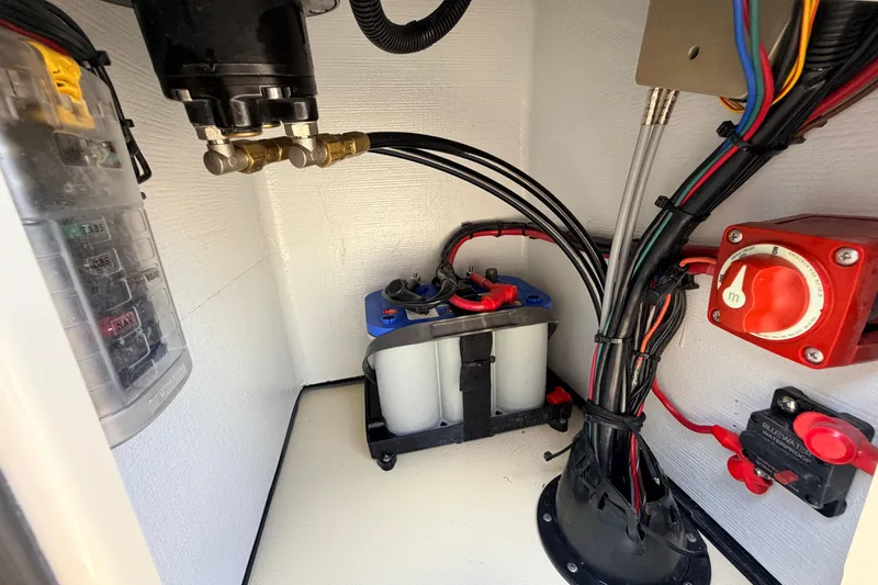 Slide: The Image of Electrical compartment of a 2025 Hell's Bay Professional boat, featuring wiring and battery setup. - 52