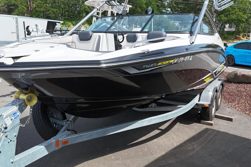Slide: The Image of 2016 Yamaha Boats 212X on trailer, sleek black and white design, parked outdoors. - 4