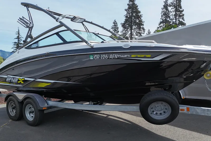 Slide: The Image of 2016 Yamaha Boats 212X on trailer, sleek black design, parked outdoors. - 2