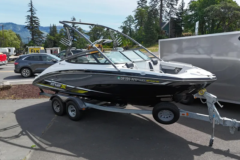 Slide: The Image of 2016 Yamaha Boats 212X on trailer, parked outdoors with scenic background. - 1