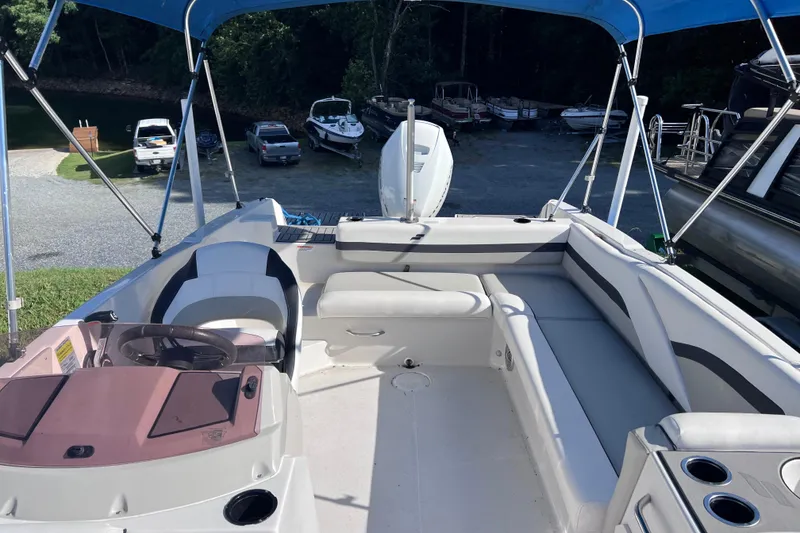 Slide: The Image of 2021 Starcraft SVX 211 OB boat interior with seating and steering wheel under blue canopy. - 7
