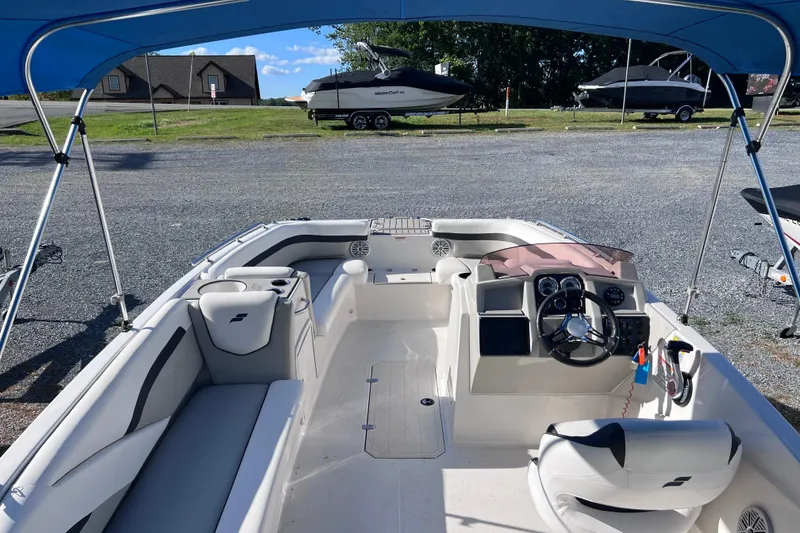 Slide: The Image of 2021 Starcraft SVX 211 OB boat interior with steering wheel and seating under blue canopy. - 9