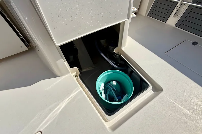 Slide: The Image of An open storage compartment on a boat with a green bucket and hoses. - 36
