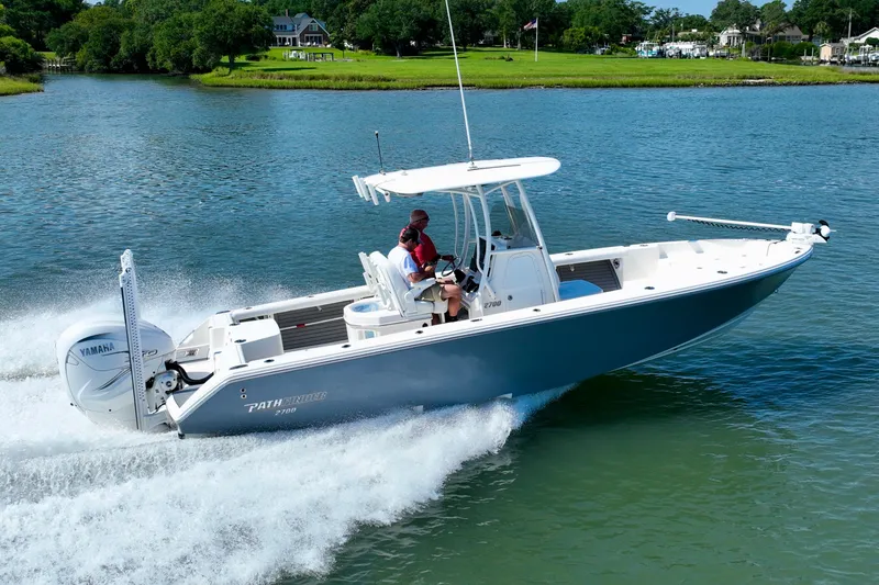 Slide: The Image of A 2022 Pathfinder 2700 Open boat speeds across calm water with green landscape in the background. - 15
