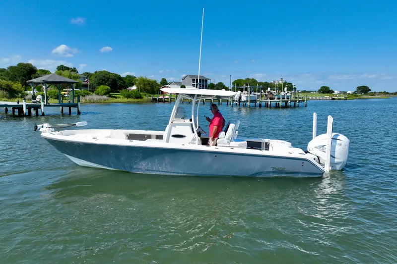 Slide: The Image of A white boat on calm water with a man on board. Docks and houses are visible in the background. - 2