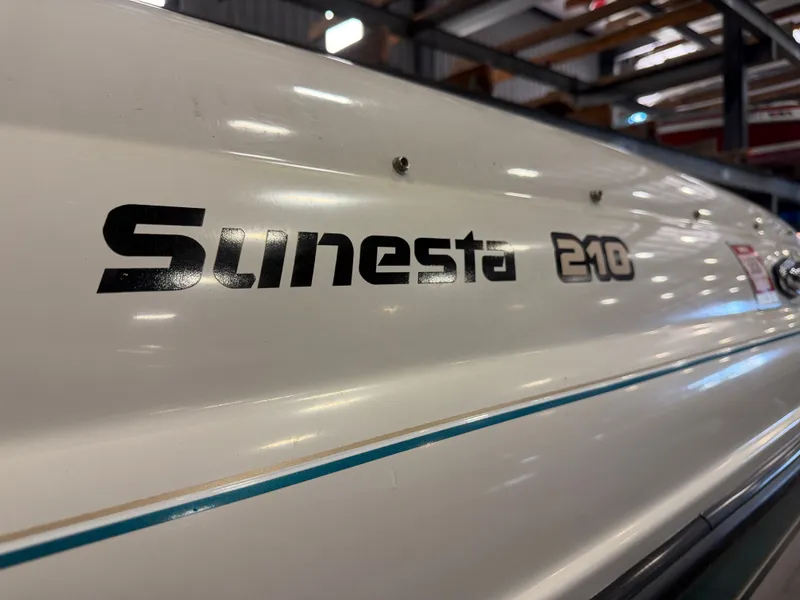 Slide: The Image of Close-up of "Sunesta 210" lettering on a white boat hull in a warehouse. - 10