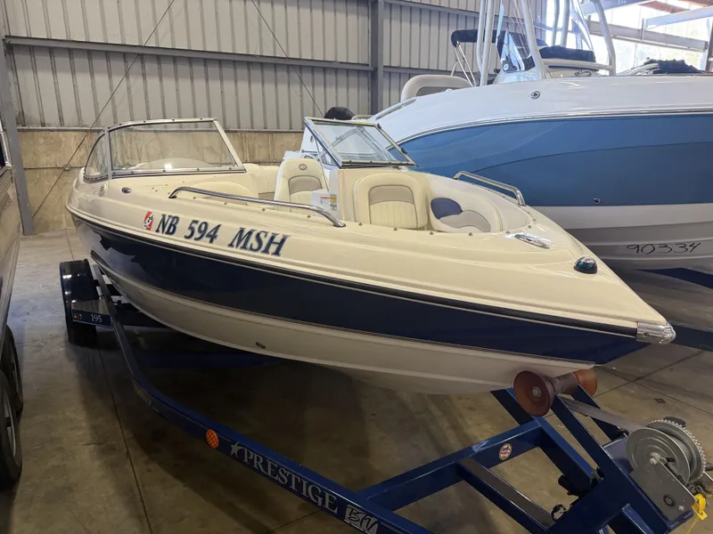 Slide: The Image of A white and blue 2006 Stingray 195 LX boat on a trailer in a warehouse. - 6