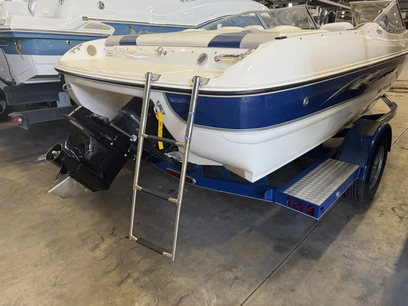 Slide: The Image of A white and blue motorboat, Stingray 195 LX model from 2006, on a trailer in a warehouse. - 8