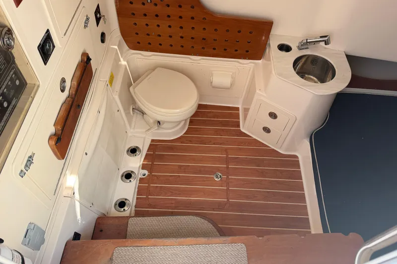 Slide: The Image of 2019 Grady-White Canyon 336 boat interior with toilet and sink, featuring wood accents. - 29