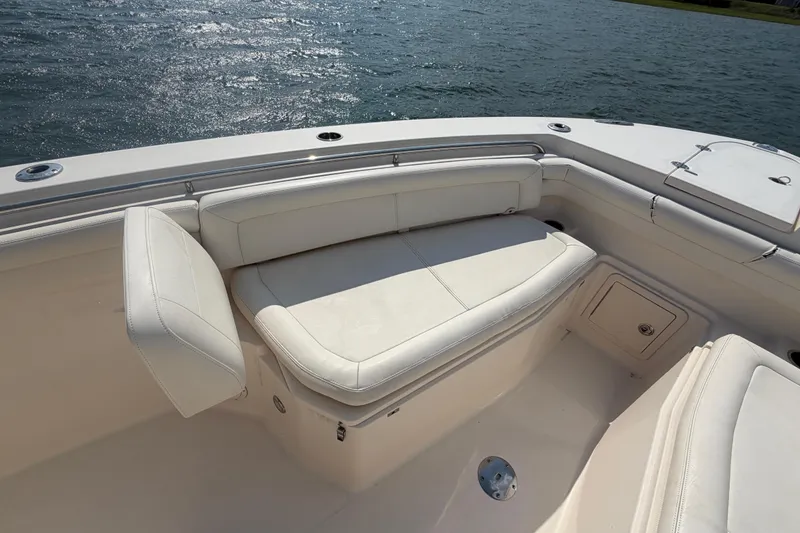 Slide: The Image of 2019 Grady-White Canyon 336 boat interior with white cushioned seating by the water. - 26