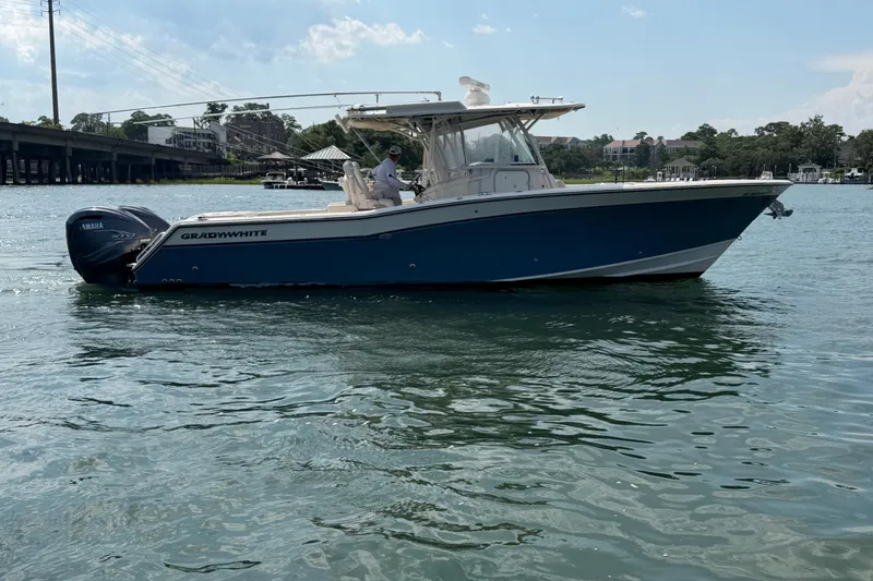 Slide: The Image of 2019 Grady-White Canyon 336 boat on water, featuring Yamaha engines, under a clear sky. - 16