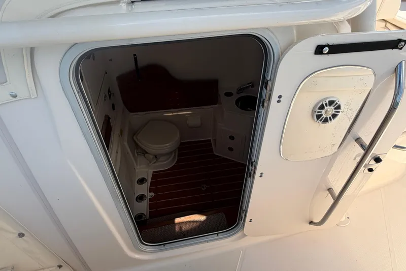 Slide: The Image of 2019 Grady-White Canyon 336 boat interior with open door revealing compact bathroom. - 36