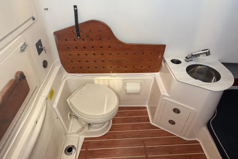 Slide: The Image of 2019 Grady-White Canyon 336 boat bathroom with toilet, sink, and wooden accents. - 33