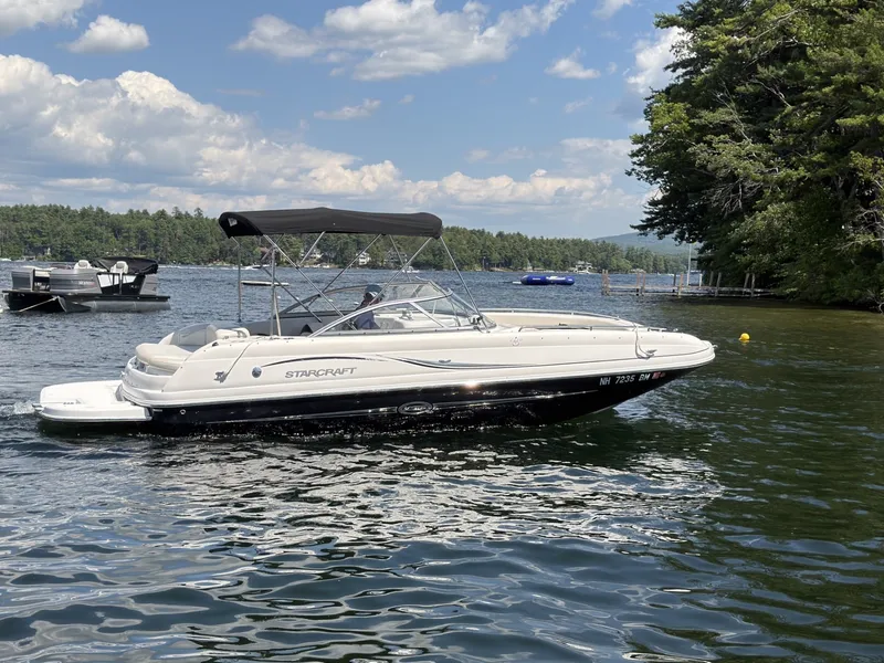 The Image of A 2011 Starcraft 2210 boat cruising on a calm lake with a wooded shoreline. - 1