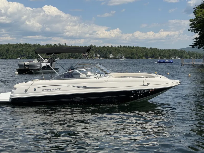 Slide: The Image of A 2011 Starcraft 2210 boat on a calm lake with a wooded shoreline in the background. - 3