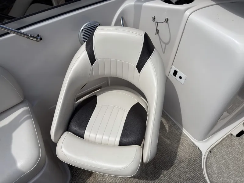 Slide: The Image of A white and black boat seat with padded stripes on a gray carpeted floor. - 18