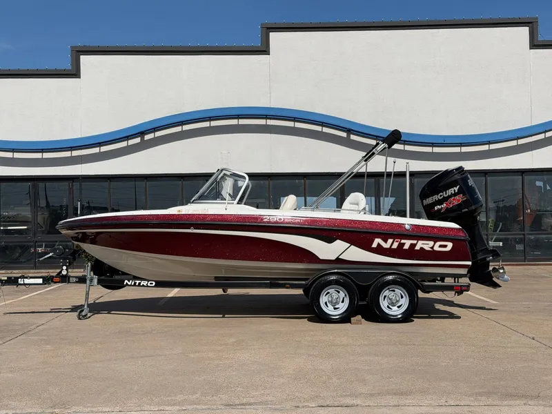 The Image of A 2013 Nitro 290 Sport boat on a trailer, parked in front of a building. - 1