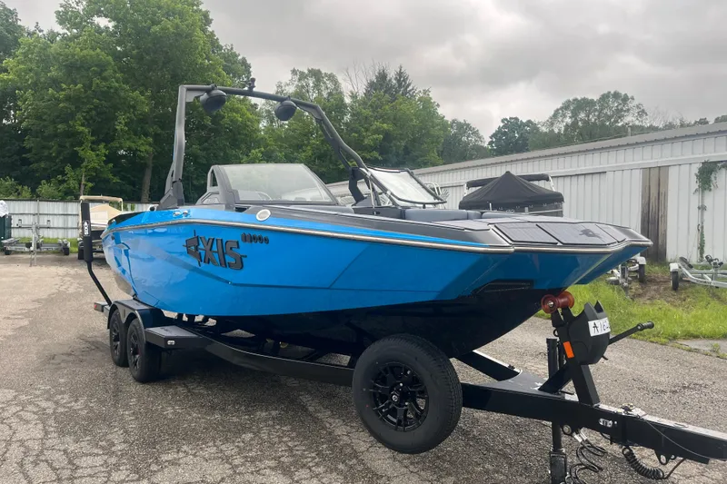 Slide: The Image of 2026 Axis A225 boat in vibrant blue on a trailer, parked outdoors. - 10