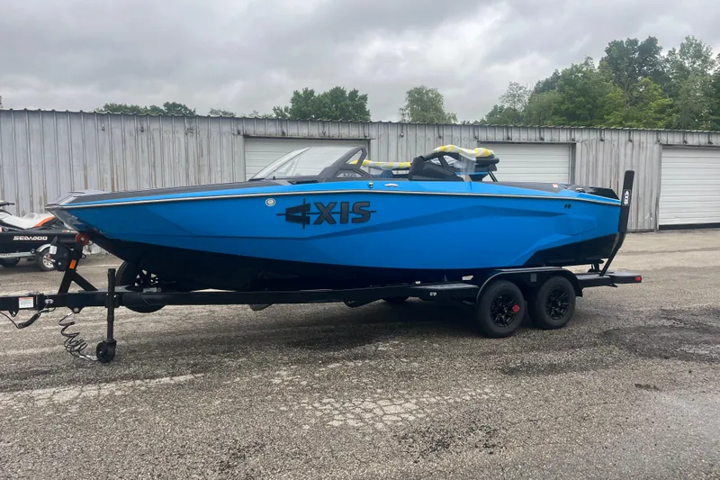 Slide: The Image of 2026 Axis A225 boat in vibrant blue on a trailer, parked outdoors. - 11