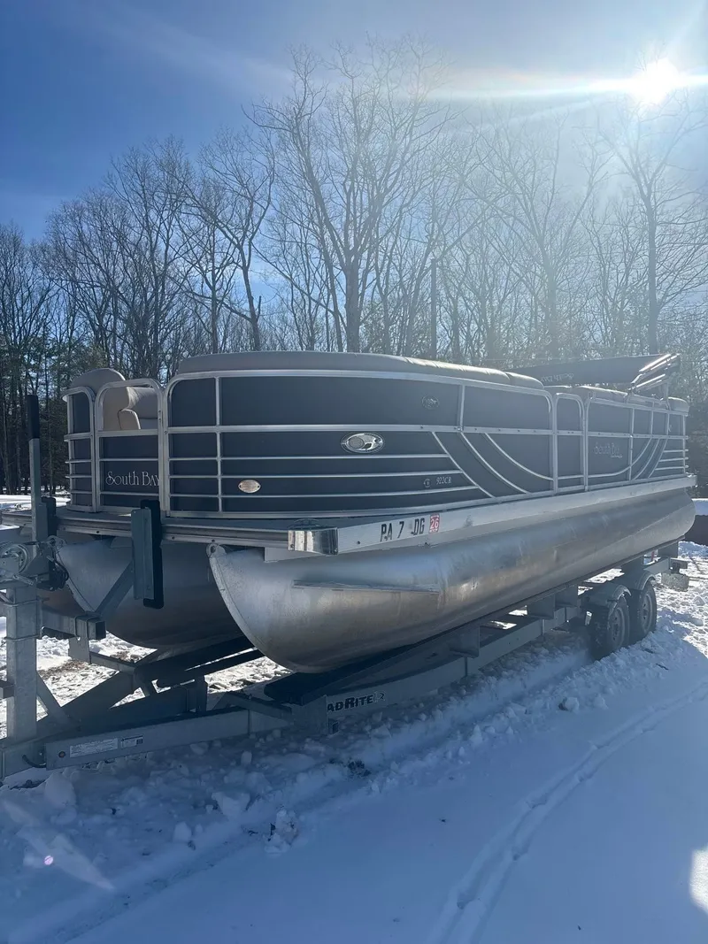 The Image of A 2008 South Bay 922CR pontoon boat sits on a trailer in the snow. - 1