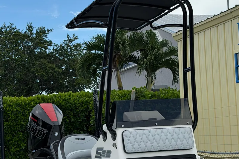 Slide: The Image of 2022 SCB S22 boat with canopy and powerful outboard motor, parked near lush greenery. - 22