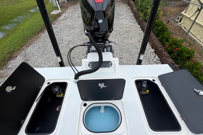 Slide: The Image of 2022 SCB S22 boat with open storage compartments and outboard motor, parked on gravel. - 21