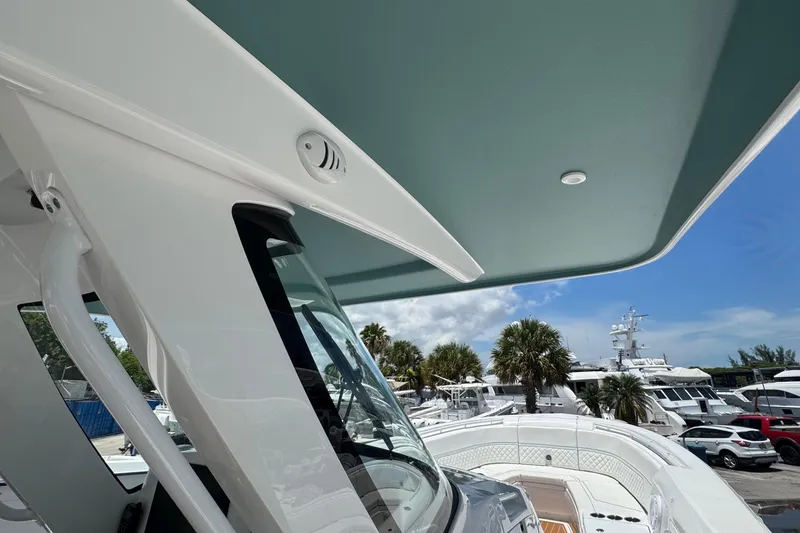 Slide: The Image of 2025 Intrepid 375 Nomad SE boat with sleek design, docked under clear blue sky. - 35