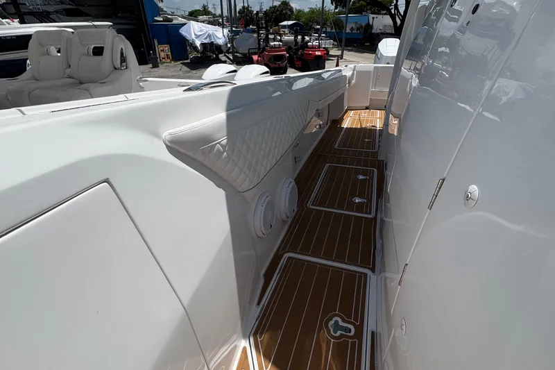 Slide: The Image of 2025 Intrepid 375 Nomad SE boat interior with sleek white seating and teak flooring. - 30