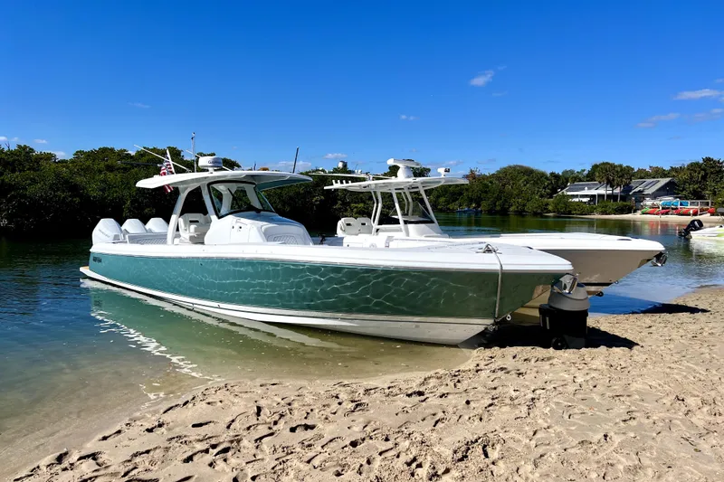 Slide: The Image of 2025 Intrepid 375 Nomad SE boat docked on sandy shore under clear blue sky. - 39