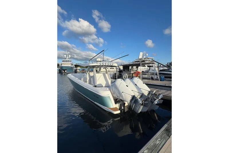 Slide: The Image of 2025 Intrepid 375 Nomad SE boat docked with triple outboard engines under a clear sky. - 37