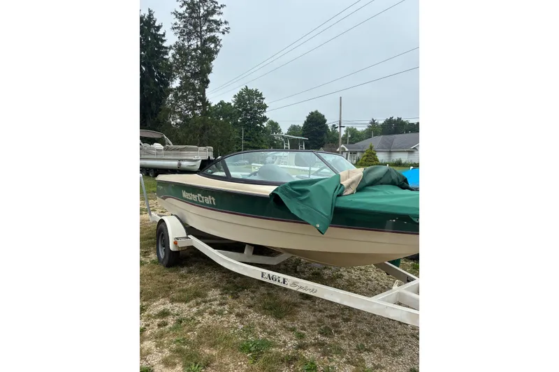 Slide: The Image of 1996 MasterCraft ProStar 190 boat on trailer, covered with green tarp, parked outdoors. - 1