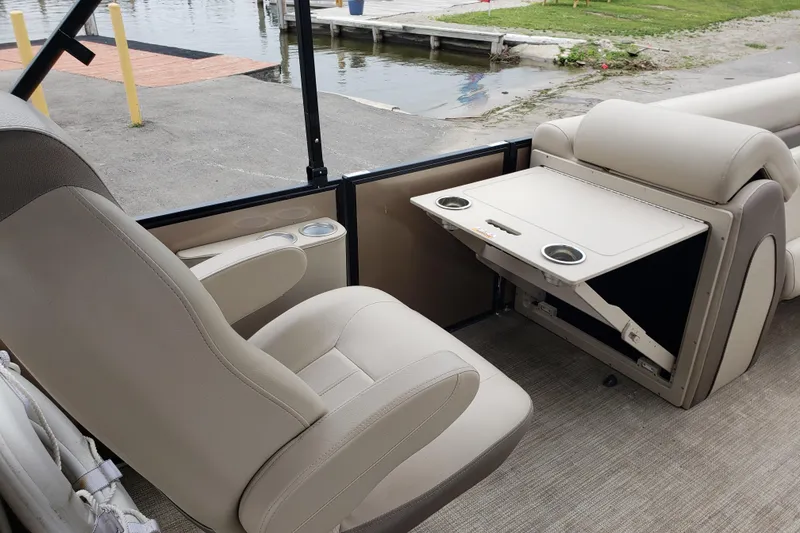 Slide: The Image of 2023 Bentley Pontoons Elite 253 Admiral interior with beige seating and foldable table. - 6