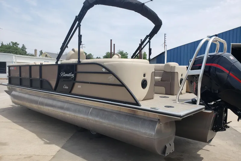 Slide: The Image of 2023 Bentley Pontoons Elite 253 Admiral, beige and black, docked with outboard motor. - 2