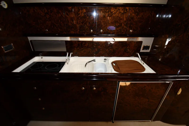Slide: The Image of Luxurious kitchen area in a 1997 Sunseeker Camargue 51 yacht with dark wood cabinetry. - 52