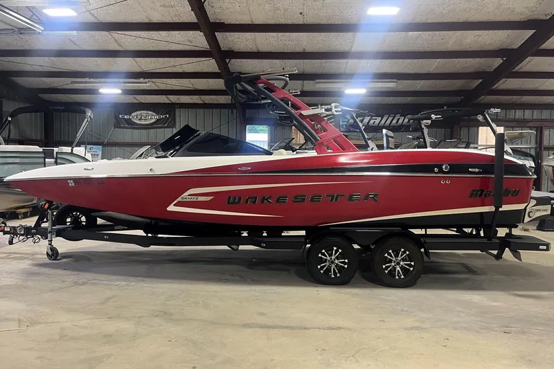 Slide: The Image of 2015 Malibu Wakesetter 24 MXZ boat in a showroom, red and white design. - 11