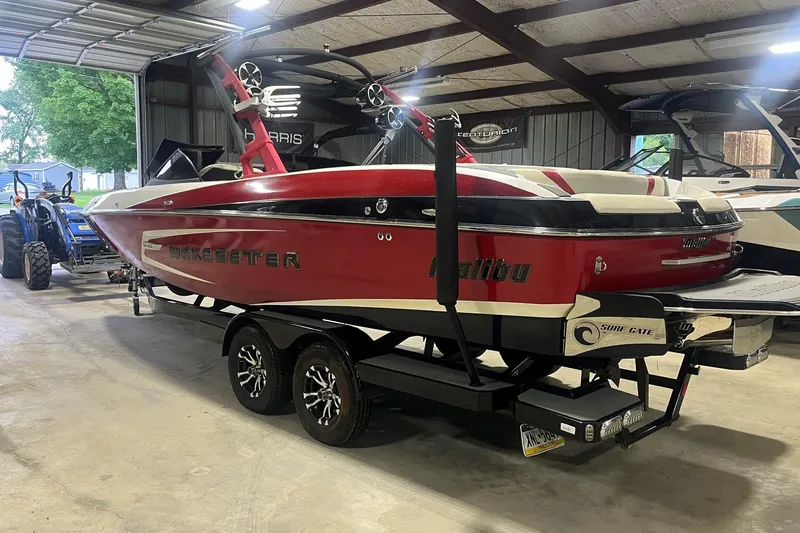 Slide: The Image of 2015 Malibu Wakesetter 24 MXZ boat in a garage, red and white design, on a trailer. - 1