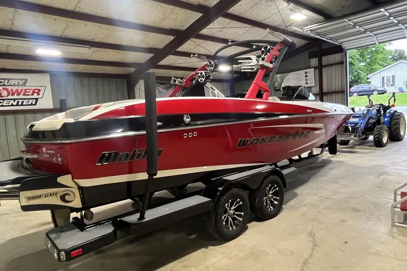 Slide: The Image of 2015 Malibu Wakesetter 24 MXZ boat in a garage, red and white design, on a trailer. - 3