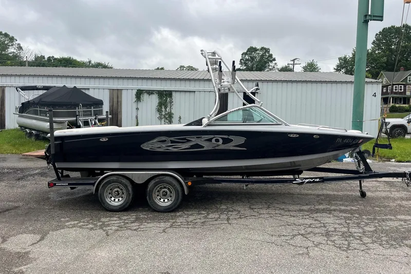 Slide: The Image of 2004 MasterCraft X-9 boat on trailer, parked outdoors near storage units. - 2