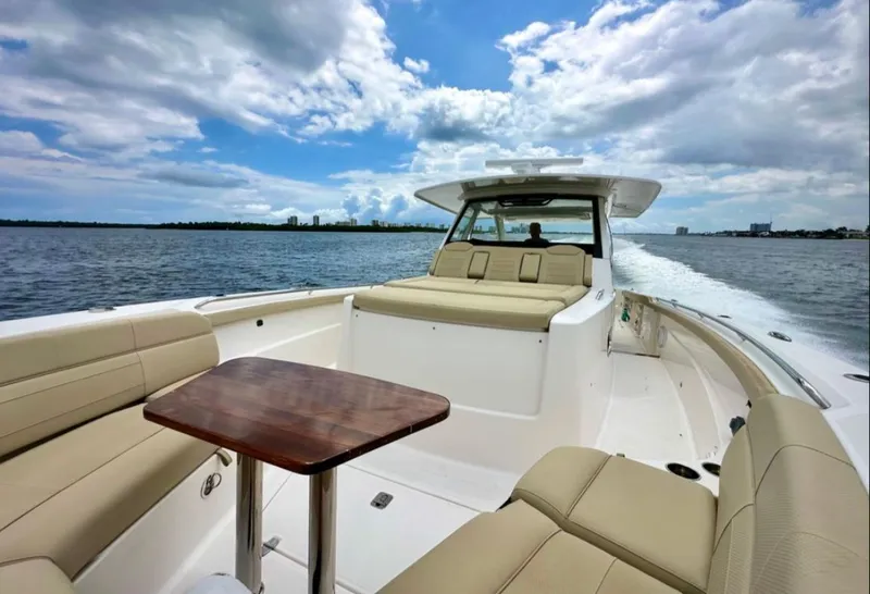 Slide: The Image of A 2017 Pursuit S 408 Sport cruising on calm water. It features beige seating and a wooden table. - 3