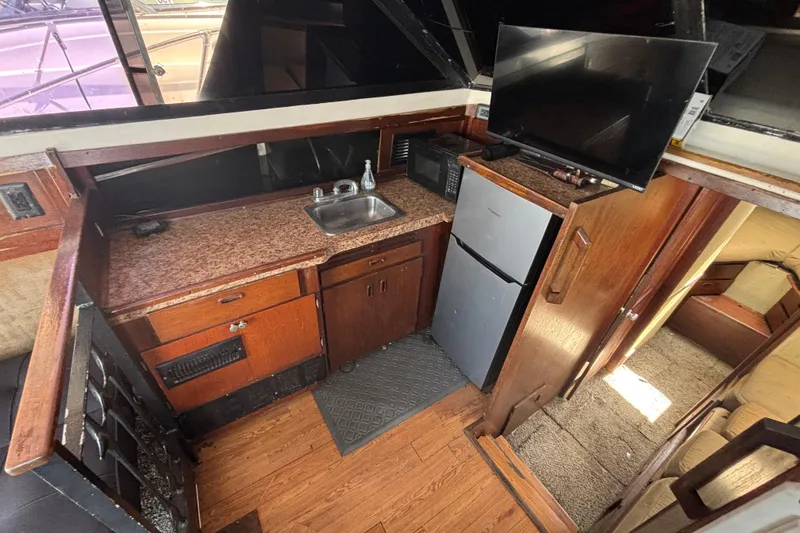 Slide: The Image of 1979 Trojan F-36 Convertible boat interior with kitchenette, sink, fridge, and TV. - 17