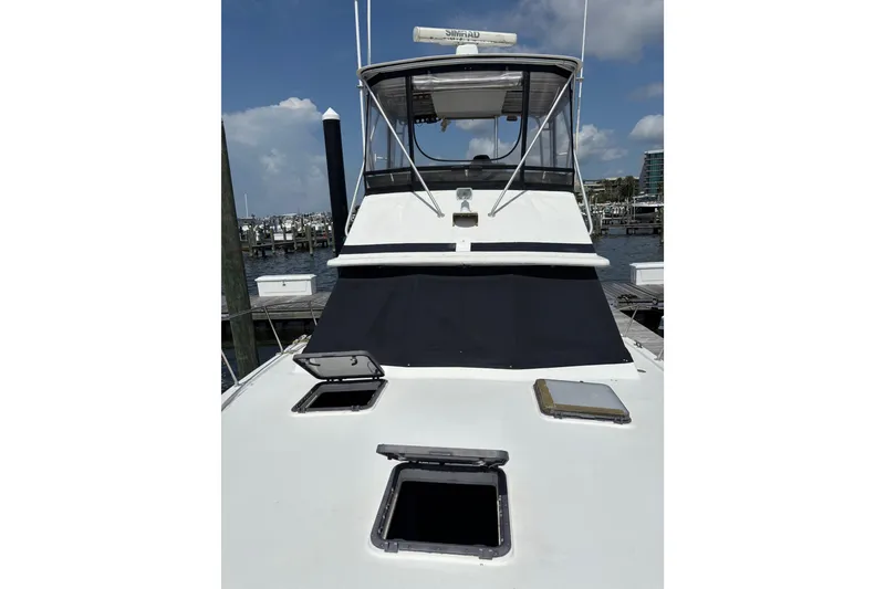 Slide: The Image of 1979 Trojan F-36 Convertible boat docked, featuring open hatches and a covered cockpit. - 12