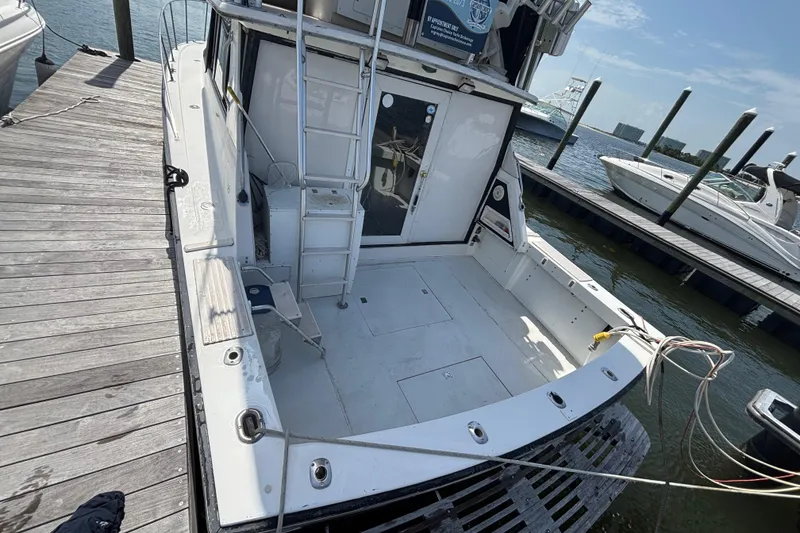 Slide: The Image of 1979 Trojan F-36 Convertible boat docked, featuring spacious deck and ladder access. - 14