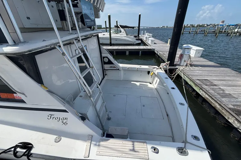 Slide: The Image of 1979 Trojan F-36 Convertible boat docked at marina, featuring spacious deck and ladder. - 13