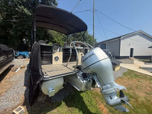 Slide: The Image of A 2017 Starcraft MX 23 C pontoon boat with a Honda outboard motor, parked on a gravel lot. - 13